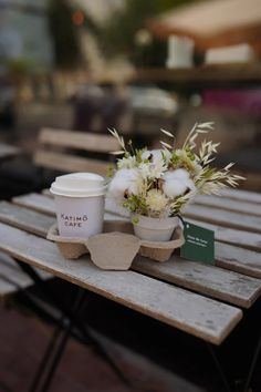 a cup of coffee sitting on top of a wooden table next to a flower pot