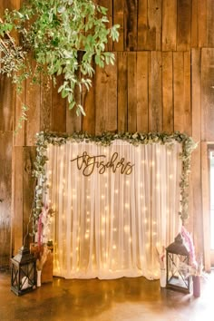 the wedding backdrop is decorated with greenery and lights