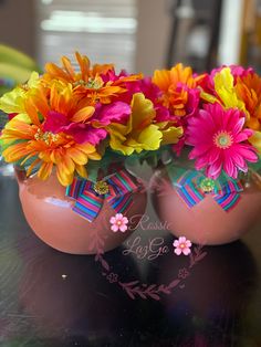 two vases filled with colorful flowers sitting on top of a black table next to each other