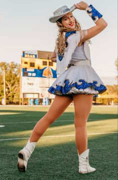 a woman in a short skirt and cowboy hat is dancing on the field with her hands behind her head