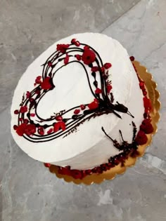 a heart shaped cake with red berries and chocolate icing on the top, sitting on a table