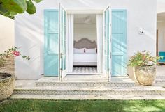 an open door leading into a bedroom with blue shutters and potted planters