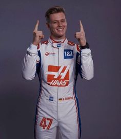 a man in a racing suit giving the thumbs up