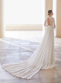 a woman in a white wedding dress standing near columns