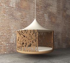 a hanging lamp made out of woven material on a wooden floor next to a brick wall