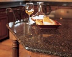 two glasses of wine and some bread on a counter top in a kitchen with granite counters