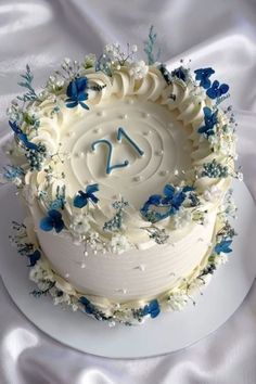 a cake with white frosting and blue flowers on the top is decorated with a number twenty