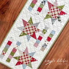 a quilted table runner with red, green and white plaid stars on the top