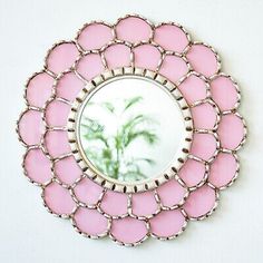 a pink flower shaped mirror hanging on the wall with a palm tree in the center