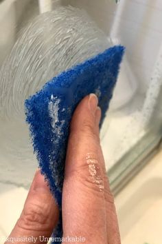 someone is cleaning the sink with blue sponge