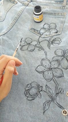 someone is drawing flowers on the back of a pair of jeans