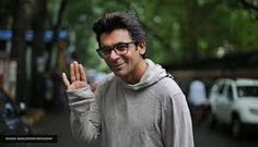 a man with glasses making the vulcan sign on his hand while walking down a street