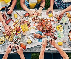 several people are sitting at a table with lobsters and corn on the cob