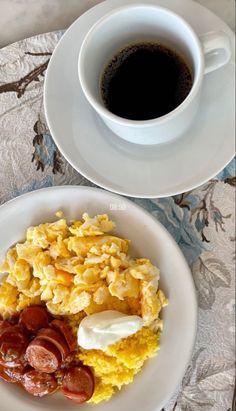 two plates with breakfast foods on them next to a cup of coffee