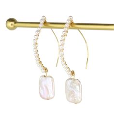 These stunning hand-wired earrings beautifully combine South Sea Pearls with a graceful dangling Keshi Pearl. With a 2.5" drop, the design features a total of 15 South Sea Pearls and two Keshi Pearls, all crafted with gold-filled metal components for an elegant finish. South Sea Pearls are believed to reduce stress, boost self-esteem, and increase wisdom, while Keshi Pearls are thought to promote prosperity, provide tranquility, and enhance memory. Gold Dangle Pearl Earrings With Shell, Shell-shaped Pearl Drop Earrings For The Beach, Handmade 14k Gold-filled Dangle Pearl Earrings, Keshi Pearl Earrings, Hypoallergenic 14k Gold-filled Dangle Pearl Earrings, Elegant 14k Gold-filled Earrings With Pearl Charm, South Sea Pearls Earrings, Pearl Charm Necklace, Sea Pearls