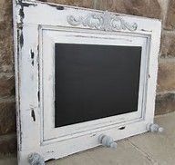 an old white frame with a chalkboard attached to the side on a brick wall