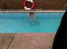 a man swimming in a pool next to a life preserver