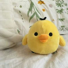 a yellow stuffed bird sitting on top of a bed