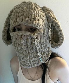 a woman wearing a crocheted hat with chains attached to it's face