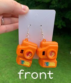 These cute Toy Camera Earrings are not only super cute, but they actually work when you're not wearing them! You can put your eye up to the viewer on the back and click through different pictures of dinosaurs. If you want to make a statement, these miniature orange camera earrings are definitely going to stand out <3 These can be worn for yourself or given as a gift! These would be perfect for any girlfriend, friend, or anyone in general that loves weird or quirky jewelry. Processing time usually takes 1-3 days and shipping takes up to 5 business days. Thank you for shopping with Kenzie's Kollection! Fun Plastic Earrings For Gifts, Pictures Of Dinosaurs, Camera Earrings, Weird Earrings, Dinosaur Pictures, Quirky Jewelry, Toy Camera, Cool Gifts For Women, Cute Toys