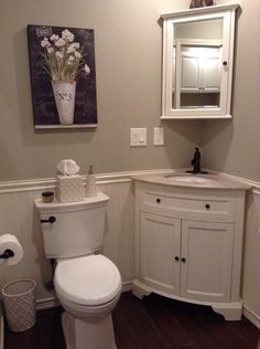 a white toilet sitting in a bathroom next to a sink and mirror on the wall