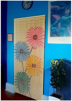 a bamboo door with flowers painted on it in front of a blue wall and clock