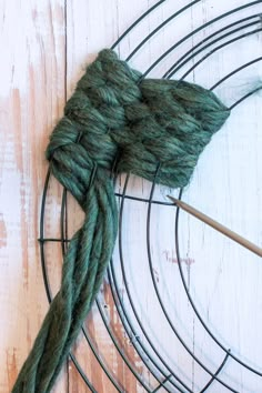 a skein of yarn sitting on top of a wire rack next to a knitting needle