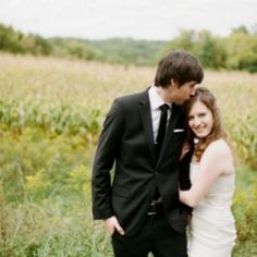 a man and woman standing next to each other in a field