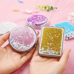 a person holding three small compact mirrors in their hand, one with glitter on it