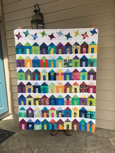 a colorful quilt hanging from the side of a house