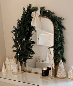 a mirror sitting on top of a white dresser next to a christmas tree and candles