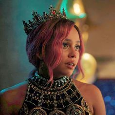 a woman with pink hair wearing a tiara and looking off into the distance while standing in a room