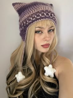 a woman with long blonde hair wearing a crocheted hat and two white flowers