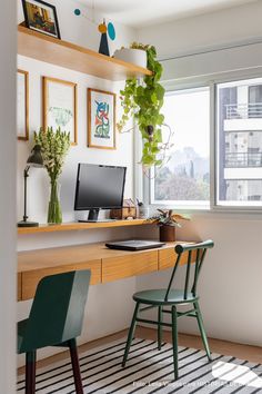 a desk with a computer on top of it next to a chair and potted plant