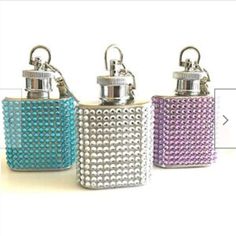 three flasks with silver and blue beads on them sitting on a white surface