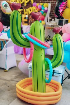 an inflatable cactus is sitting on the ground next to balloons and streamers