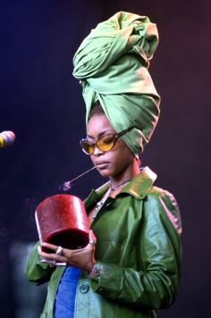 a woman wearing a green turban and holding a red bucket