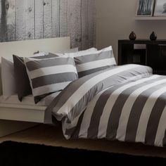 a bed with grey and white striped comforter on it's side in a bedroom