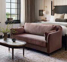 a bed room with a neatly made bed next to a couch and a table in front of it