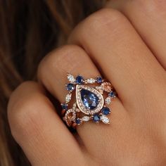 a woman's hand with a blue and white diamond ring on her left hand