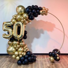 a balloon arch with the number 50 in gold, black and silver balloons attached to it