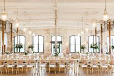 a large room with tables and chairs set up for a wedding reception in front of windows