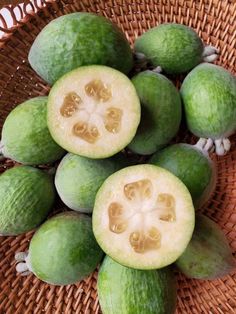 a bunch of green fruit sitting on top of a woven basket next to each other