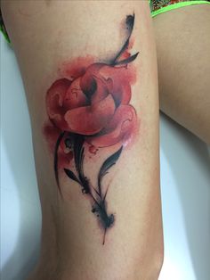 a woman's thigh with a watercolor painting style flower tattoo on her leg