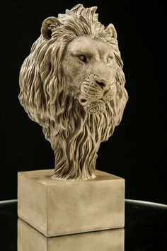 a statue of a lion is shown on a black surface with its head turned to the side