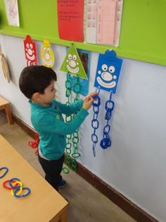 a little boy that is standing in front of some magnets on a wall with chains