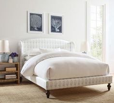 a white bed sitting in a bedroom next to two framed pictures