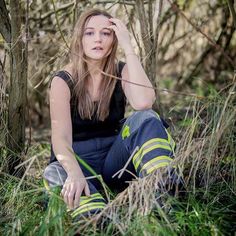 a woman sitting in the grass with her hand on her head and looking at the camera