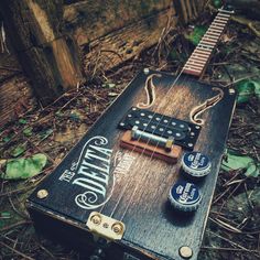 an old guitar laying on the ground next to two empty beer cans and some wood