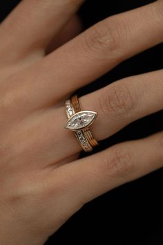 a woman's hand with two rings on her fingers and an engagement ring in the middle